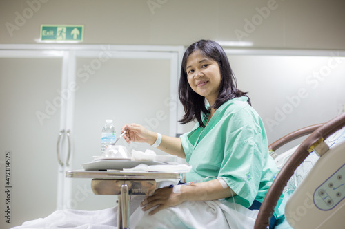 Happy female Patient Enjoying Meal In Hospital Bed