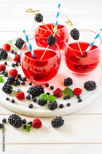 Summer beverage with raspberry and blackberry on white wooden table. Soft focus