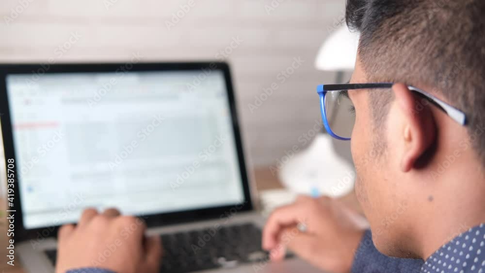 rear view of young man using laptop with blank screen on office desk.