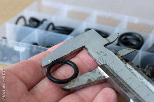 Measuring the diameter of the rubber O-ring with a caliper. An old measuring tool and a set of sealing gaskets for pneumatics and hydraulics.