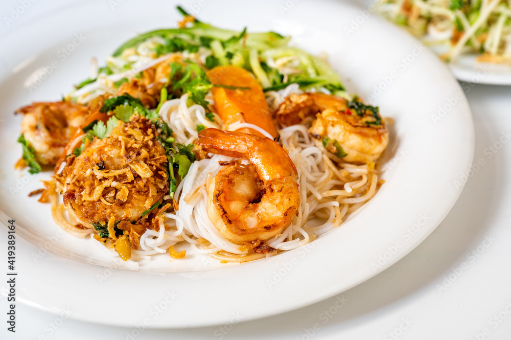 Asian style food with shrimp, noodle, onion and vegetable.