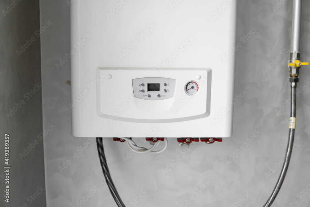 White modern home gas boiler mounted on a grey wall on a kitchen. Water heater. Water heating, ecology. White modern home gas boiler mounted on a grey wall on a kitchen. Water heater. Water heating, ecology.