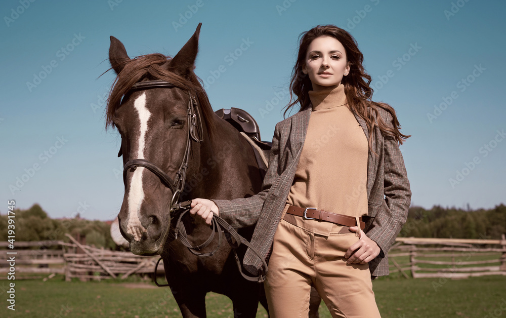 Fototapeta premium Beautiful brunette woman in an elegant checkered jacket with a horse