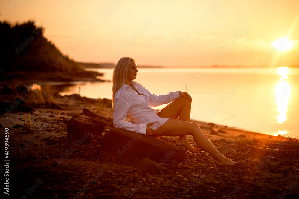 blonde girl in a white man's shirt on the riverbank, selective focus