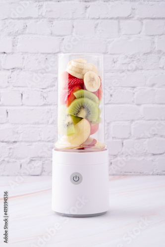 Mixed fruit, apple, kiwi, banana and strawberry in portable blender ready to make smoothie