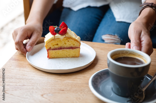 Closeup image of a woman holding a cake and coffee cup in cafe