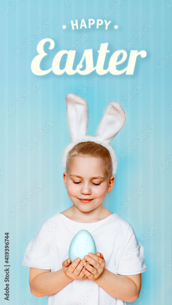 Little baby cute boy smile beaming wearing bunny ears and white t-shirt, standing to hold Easter eggs. On blue background with copy space Little baby cute boy smile beaming wearing bunny ears and white t-shirt, standing to hold Easter eggs. On blue background with copy space