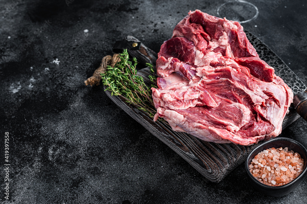 Raw Boneless Leg of Lamb meat on wooden cutting board. Black background. Top view. Copy space