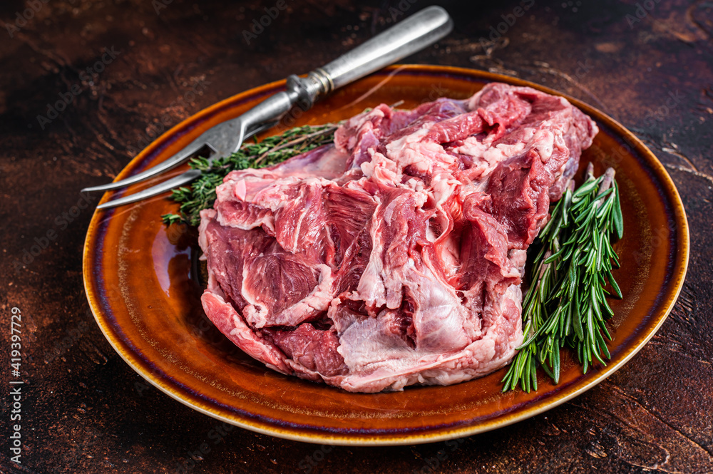 Raw Boneless Lamb leg meat in rustic plate with thyme. Dark background. Top view