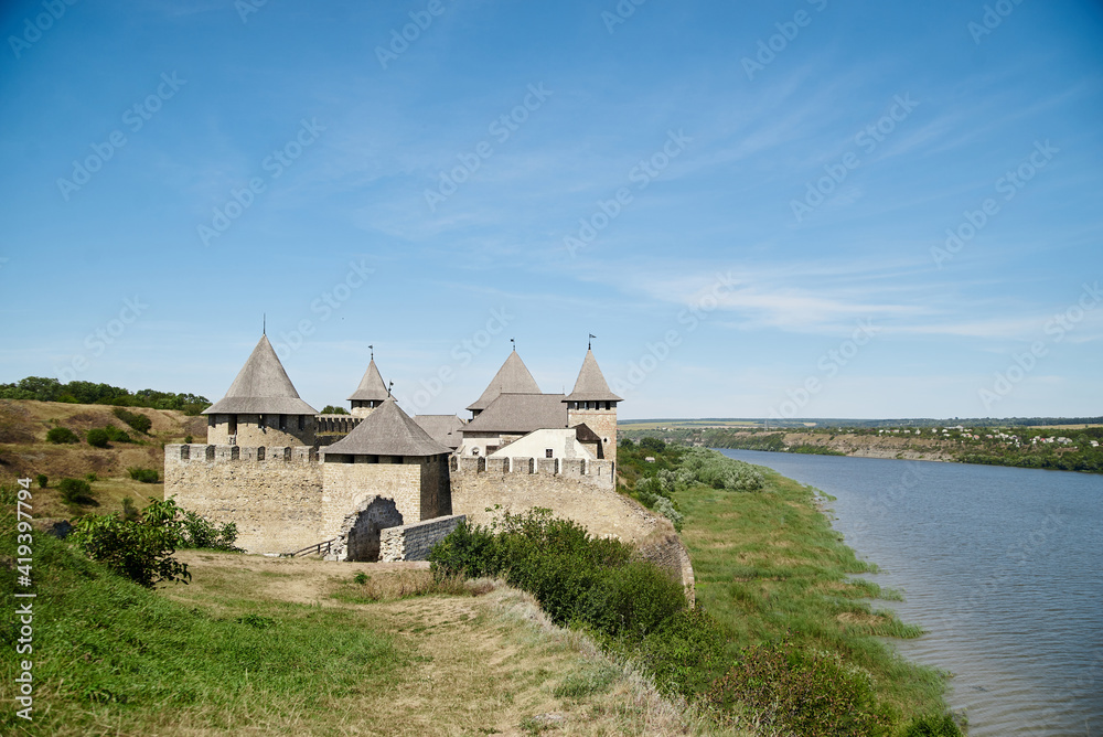 Scenic view over ancient fortress, surrounded by river. Beautiful natural countryside landscape with blue sunny sky, bright yellow plants. Summer getaway vacation. Historical sightseeing tour Scenic view over ancient fortress, surrounded by river. Beautiful natural countryside landscape with blue sunny sky, bright yellow plants. Summer getaway vacation. Historical sightseeing tour