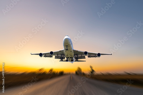 front image commercial passenger aircraft or cargo transportation airplane fly up taking off from airport runway motion blur effect in morning with sunrises landscape view