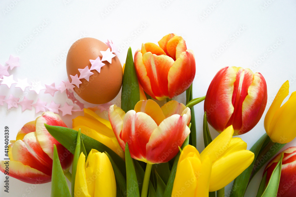 a bouquet of colorful tulips and a brown chicken egg. beautiful spring flowers. background for decoration for the Easter holiday. a bouquet of colorful tulips and a brown chicken egg. beautiful spring flowers. background for decoration for the Easter holiday.