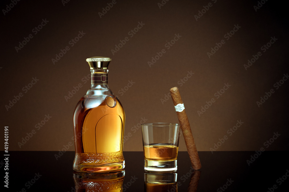 close up view of cigar, bottle of cognac and a glass aside on brown back. close up view of cigar, bottle of cognac and a glass aside on brown back.
