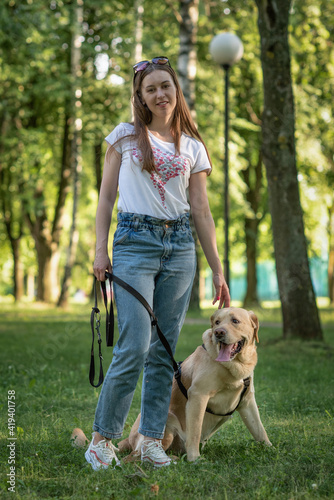 Young beautiful girl with a labrador retriever in a summer park.