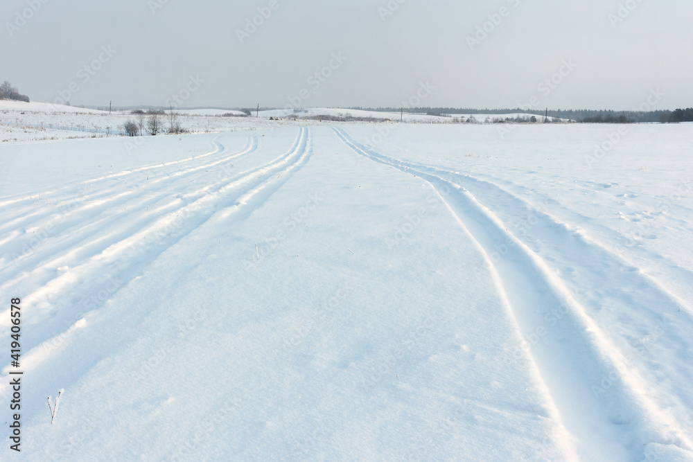Winter snow field with snowmobile tracks