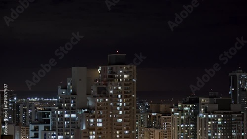 Timelapse of Full moon rising behind clouds and above city skyline and buildings. 4K UHD