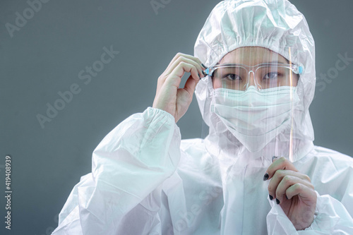 Female doctor or nurse wearing protective suit and protective mask and goggles banner to protect COVID-19 infection. Outbreak COVID-19, Medical, Healthcare and Quarantine concept.