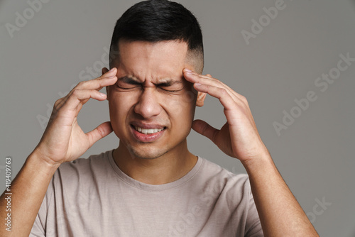 Displeased handsome guy with headache rubbing his temples