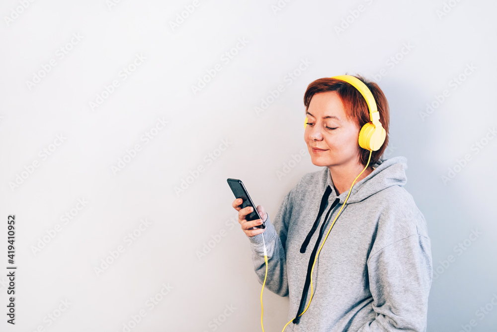 Beautiful woman in gray sweatshirt and yellow headphones Beautiful woman in gray sweatshirt and yellow headphones