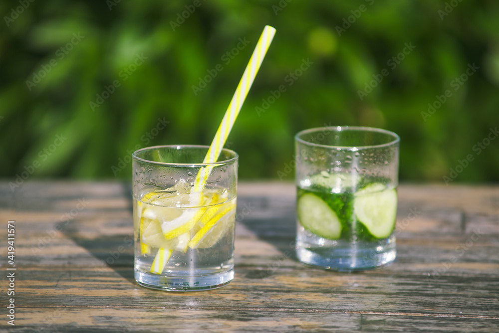 fresh lemon and cucumber lemonade. drinking straw in glass. chopped fruit slices in water