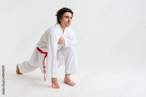Confident young karate man warming up isolated