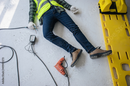 Accident electrocuted, Unconscious electrician worker lying on the floor with stretcher of paramedic team.