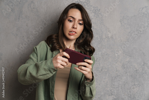 Tense charming girl playing online game on mobile phone