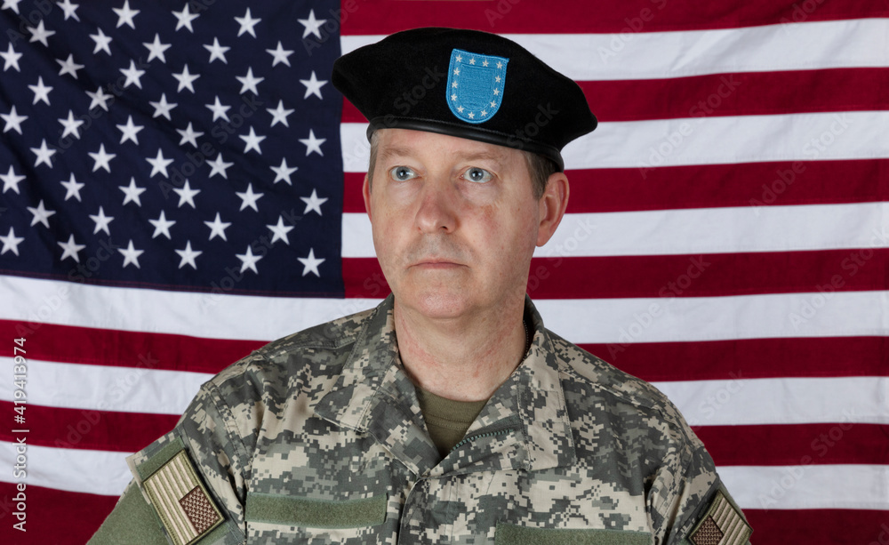 Man wearing military outer shirt and beret with US flag in background Man wearing military outer shirt and beret with US flag in background