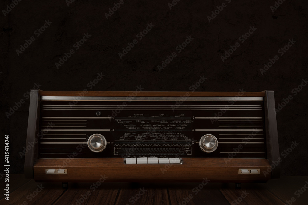 Obraz premium Old antique radio on a yellow background with dark brown wooden table
