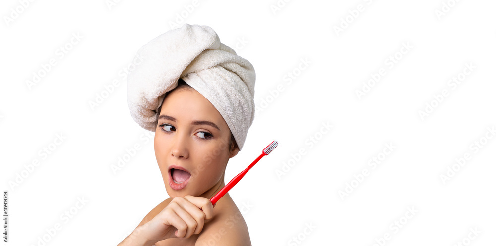 Banner- long format. Close up shot of happy joyful funny young woman with towel on head, brushes teeth actively, holding toothbrush, opens mouth broadly, shows bare shoulders, cares of oral hygiene Banner- long format. Close up shot of happy joyful funny young woman with towel on head, brushes teeth actively, holding toothbrush, opens mouth broadly, shows bare shoulders, cares of oral hygiene