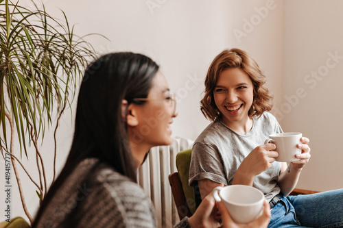 Foto Selective focus of laughing friends drinking coffee at home