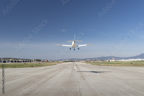 Light propeller aircraft landing on runway, close up symmetrical view