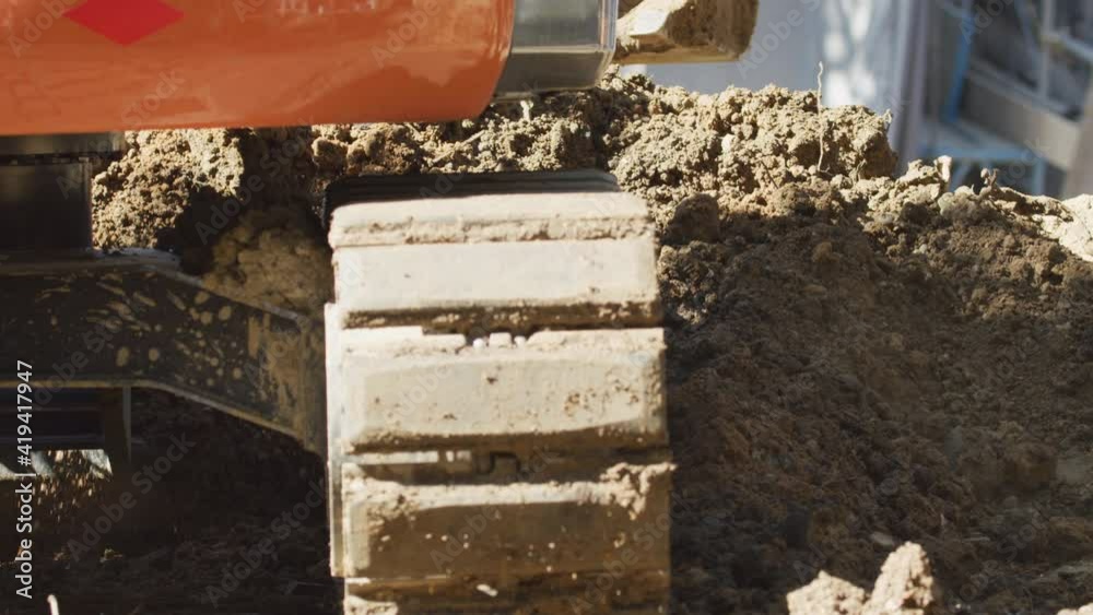A low angle of a small backhoe digging a drainage ditch. Earth moving equipment A low angle of a small backhoe digging a drainage ditch. Earth moving equipment
