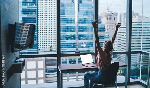 Happy woman raising hands up in modern workplace