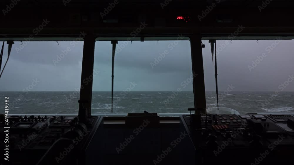 Sea view from the bridge of the ship. Storm. The ship is rocking. High waves. White foam on the water. Windshield wiper works.