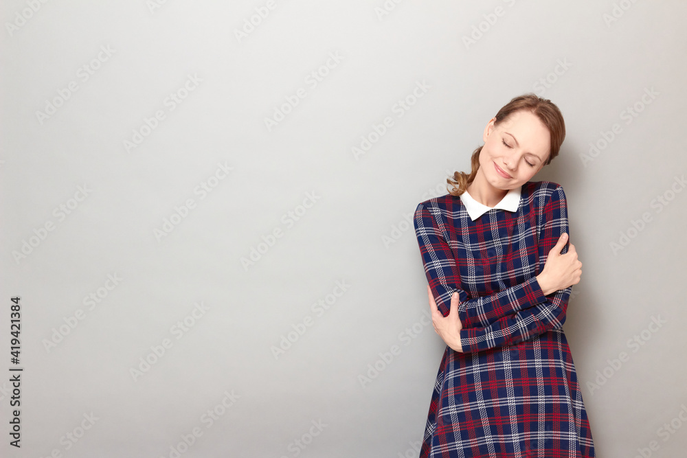 Portrait of happy girl hugging herself and smiling with closed eyes Portrait of happy girl hugging herself and smiling with closed eyes