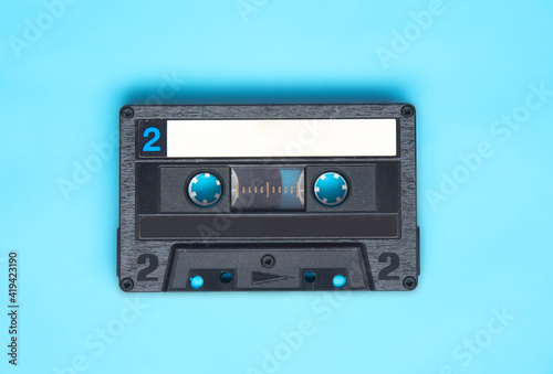 Retro audio cassette tape on turquoise background.