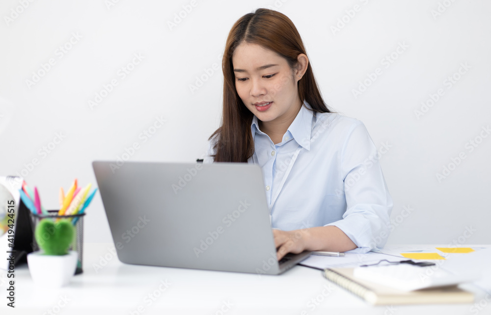 Young Asian office worker presses her finger on a laptop keyboard to analyze financial data and summarize her work in a private office, Office workers, beautiful female employee wearing a blue shirt. Young Asian office worker presses her finger on a laptop keyboard to analyze financial data and summarize her work in a private office, Office workers, beautiful female employee wearing a blue shirt.