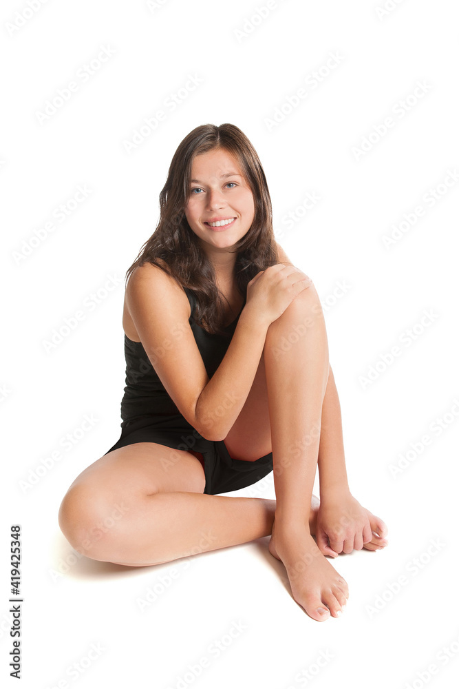 Beautiful young woman wearing black sportswear sitting in front of white studio background Beautiful young woman wearing black sportswear sitting in front of white studio background