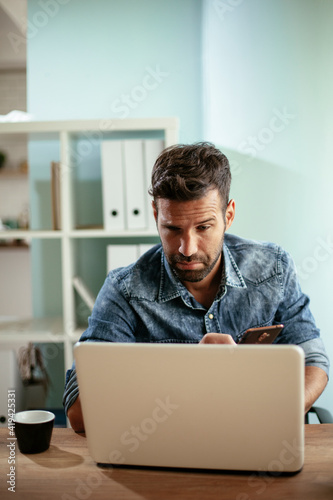 Young businessman working on laptop at office. Businessman sitting at office desk working on new project.