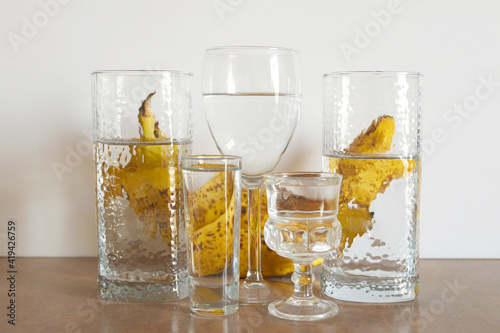Bananas behind the glass of water. Reflection of bananas in a glass of water. Abstract food background.