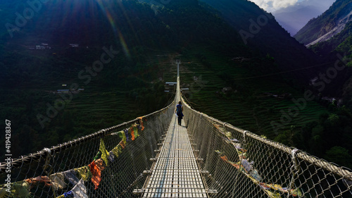 Girl crossing New Bridge: the longest suspension bridge in Himalaya mountain range in Nepal