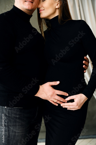 pregnant woman with a big belly in the arms of her husband. young pregnant married couple. last month of pregnancy. happy future parents © Vadym