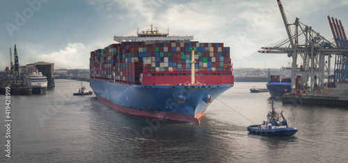 Fotografie Container terminal in the port of Hamburg with large container ship and tugs
