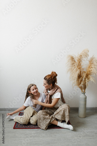 Mother and child talk sitting at home on the floor next to the wall