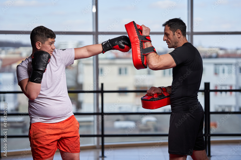 Overweight kickboxer hitting mitts