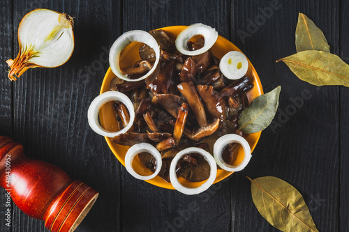  Armillaria mellea or honey fungus marinated in a yellow plate with spices and onions on a vintage table. Idea for a delicious snack for lunch. Top view photo