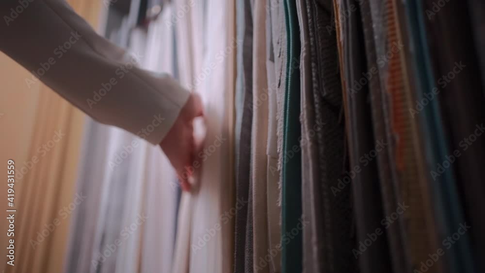closeup of female hand choosing fabric cloth for curtain at showroom or shop