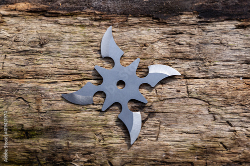 Shuriken (throwing star), traditional japanese ninja cold weapon stuck in wooden background photo