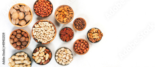 Assortment of nuts in bowls. Cashews, hazelnuts, walnuts, pistachios, pecans, pine nuts, peanuts, macadamia, almonds, brazil nuts. Food mix on white background, top view, copy space